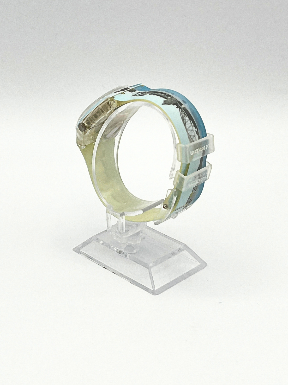 A vintage Casio digital watch with a light blue and white patterned resin band, displayed on a clear acrylic stand against a white background.