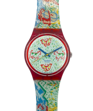 A Swatch wristwatch featuring a vibrant, multicolored abstract pattern on the strap and dial, with a translucent red case and blue hands.