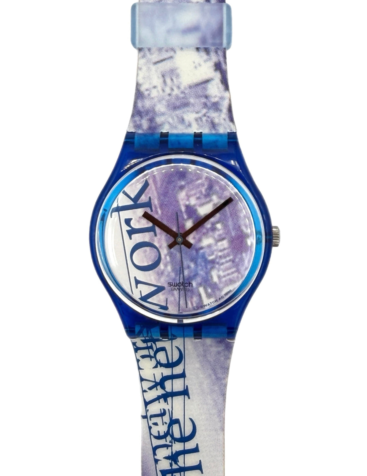 A Swatch wristwatch with a blue translucent case and a patterned strap featuring the words 'NEW YORK' and 'BEYOND THE MIST' in blue over a white and purple cityscape print.