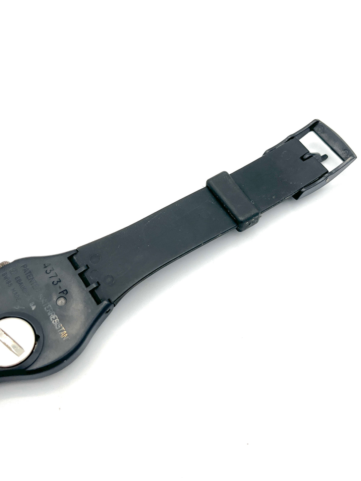 A black plastic watch strap end with a buckle and a small circular silver metal detail, photographed on a plain white background.