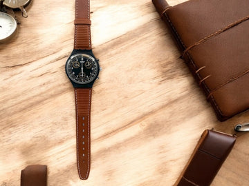 A new, unopened replacement band for a Pop Swatch watch, featuring a vibrant orange textile strap with a matching orange dial, packaged in a clear plastic case.