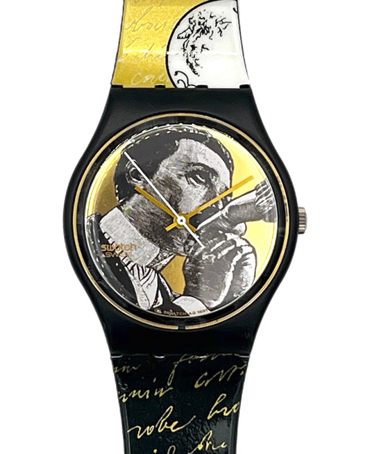 A Swatch-style wristwatch with a black case and a patterned strap featuring black-and-white portrait artwork, gold script, and gold accents, including a gold dial and hands.