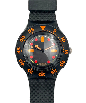 A Swatch wristwatch with a black textured strap, black bezel, and a black dial featuring bright orange and red accents.