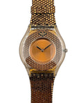 Gold watch with a textured band on a white background