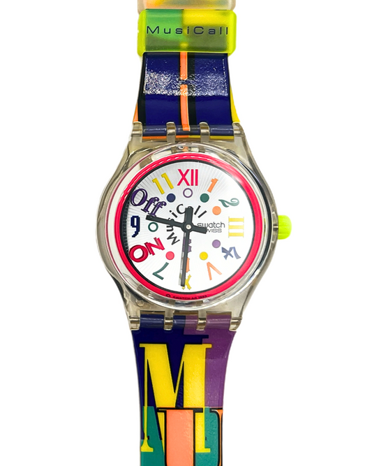 Swatch MusicCall watch with a clear case, colorful abstract dial, and a multicolor silicone strap featuring the letters 'M', 'U', and 'S' in yellow, orange, and green.